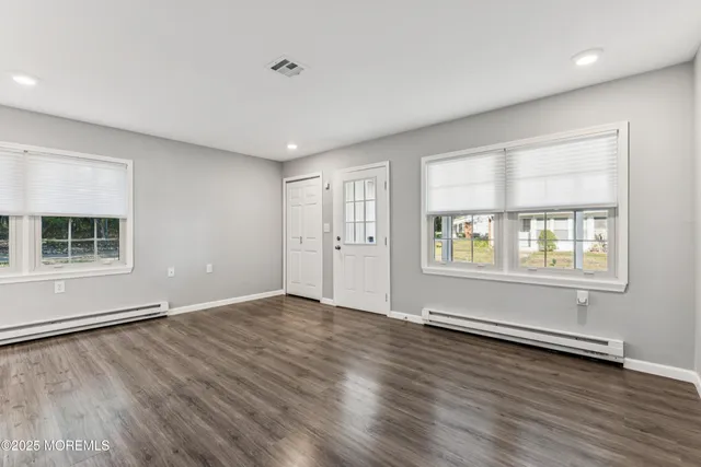 an empty room with wooden floor and windows