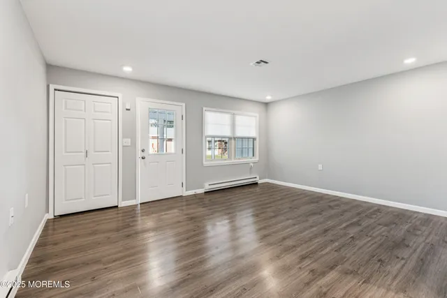 a view of an empty room with window and wooden floor
