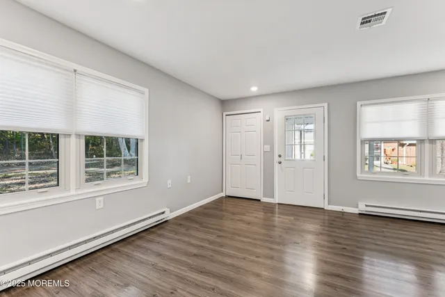 an empty room with wooden floor and windows