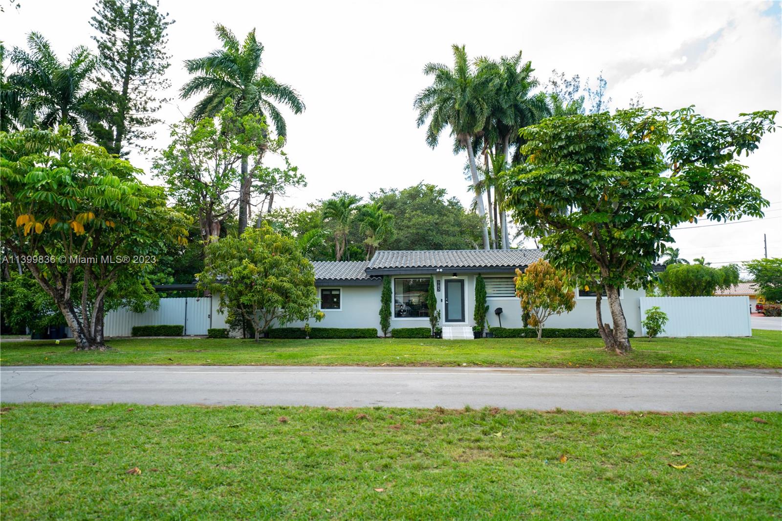 a view of a house with a big yard and palm trees