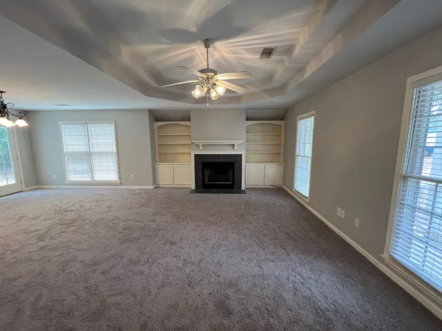 an empty room with fireplace chandelier and windows