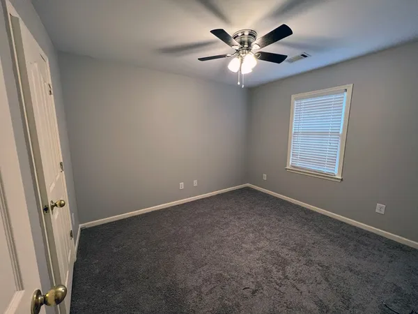 an empty room with windows and fan