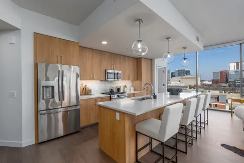 a kitchen with stainless steel appliances granite countertop a refrigerator a stove a sink a dining table and chairs