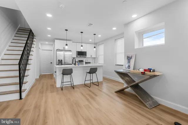 a living room with furniture and kitchen view with wooden floor