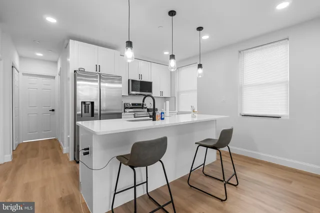 a kitchen with stainless steel appliances a refrigerator a sink dishwasher a stove and white cabinets with wooden floor