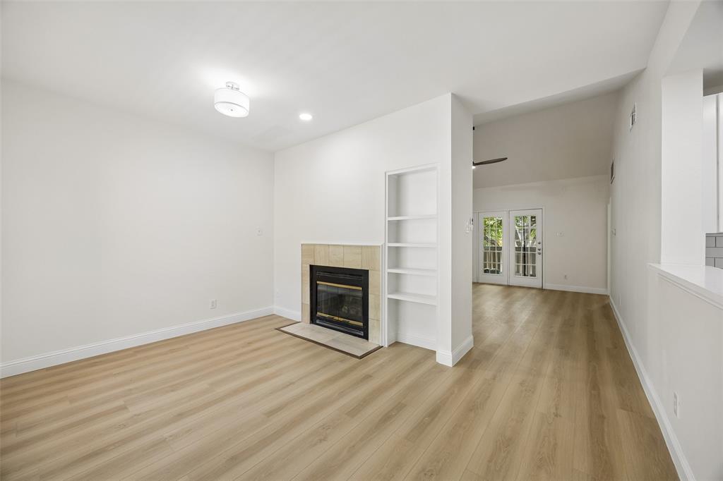 12660 Hillcrest Road, Unit 7205 Dallas, TX 75230 - Photo 8 of 25 Living space featuring light wood-finish flooring, a built-in fireplace with a tiled surround, integrated shelving, and a vaulted ceiling