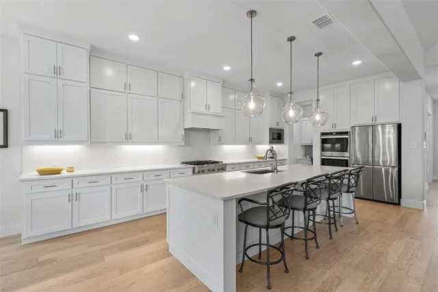 a kitchen with stainless steel appliances kitchen island granite countertop a stove a sink a refrigerator and chairs