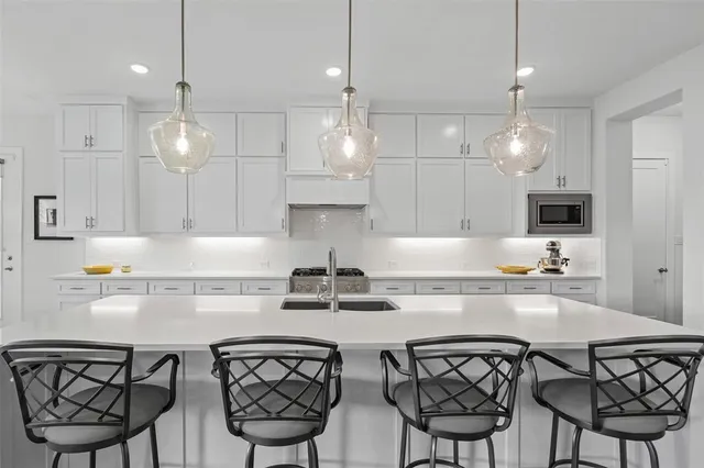 a kitchen with stainless steel appliances a table chairs and white cabinets