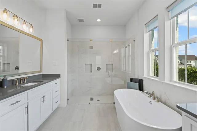 a bathroom with a double vanity sink a large mirror and a bathtub