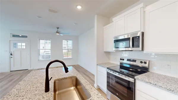 a kitchen with stainless steel appliances granite countertop a stove a sink and a microwave