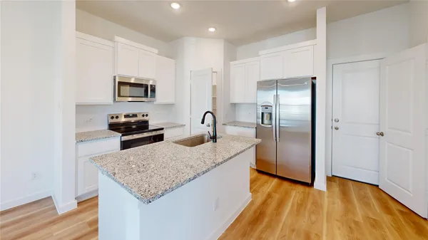 a kitchen with stainless steel appliances granite countertop a refrigerator a stove and a sink with wooden floor