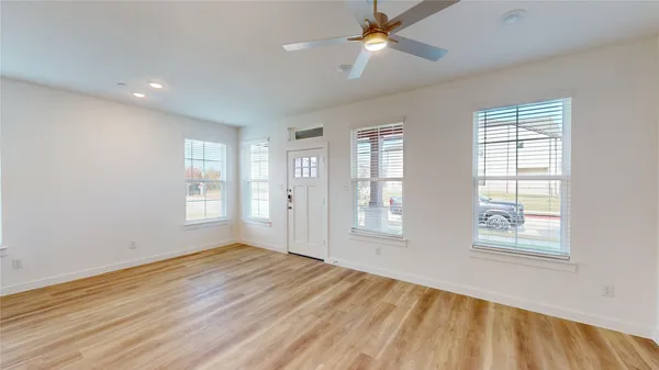 a view of empty room with wooden floor and fan