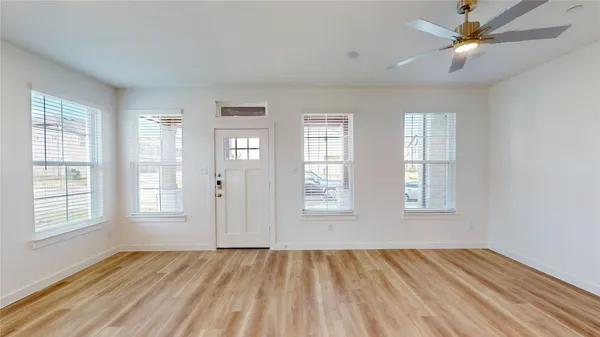a view of an empty room with a window and wooden floor