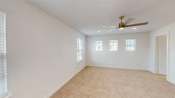 an empty room with windows and ceiling fan