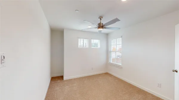 a view of an empty room with a window and a ceiling fan