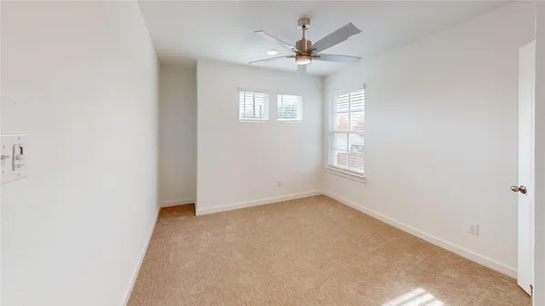 an empty room with a window and ceiling fan