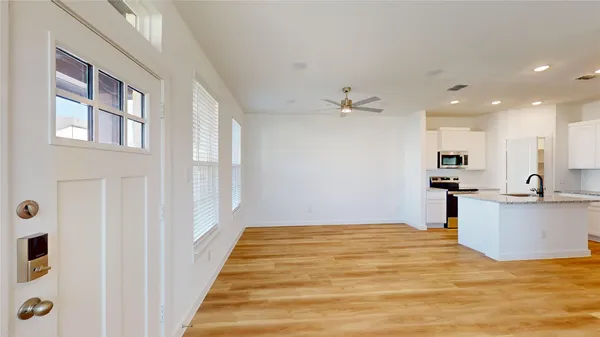 a view of kitchen and empty room with wooden floor