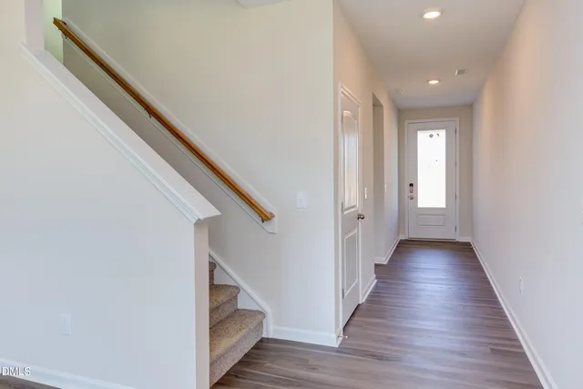 a view of a hallway with wooden floor and staircase