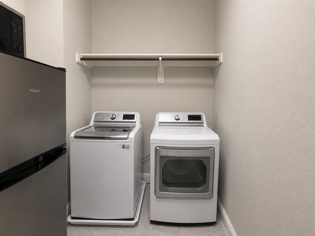 8235 Snapdragon Way Dallas, TX 75252 - Photo 21 of 29 Dedicated laundry area featuring a white top-load washer, a white front-load dryer, and a wall-mounted shelving unit