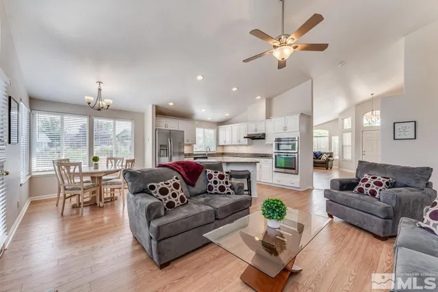 a living room with furniture kitchen area and a chandelier