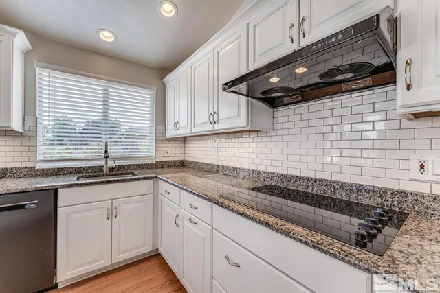 a kitchen with granite countertop stainless steel appliances a sink a white cabinets and a window