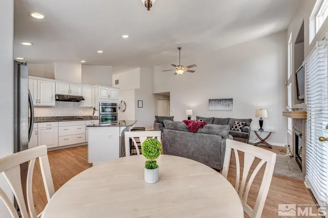 a kitchen with stainless steel appliances granite countertop a refrigerator a sink dishwasher a dining table and chairs with wooden floor