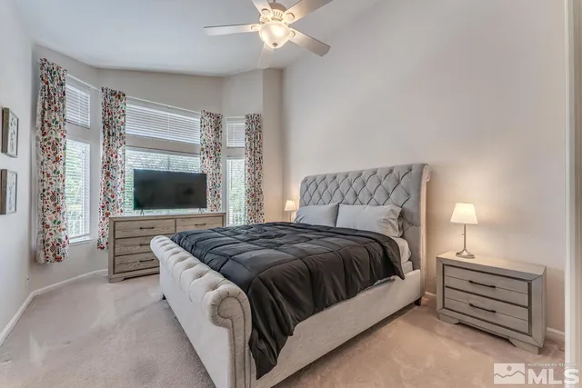 a spacious bedroom with a bed and a flat screen tv