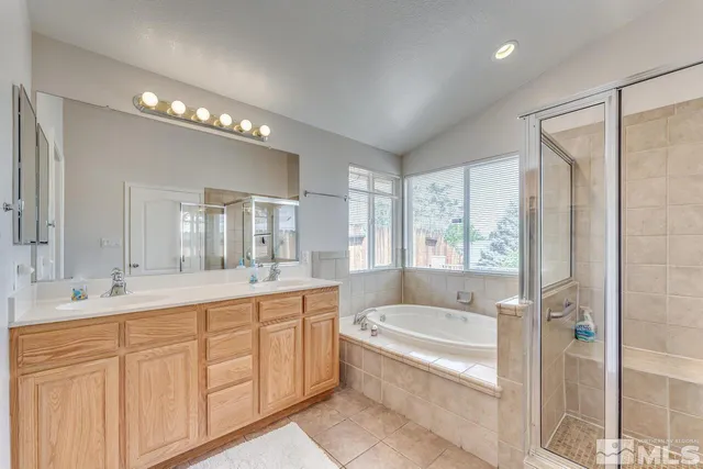 a bathroom with a tub a sink shower double vanity and mirror