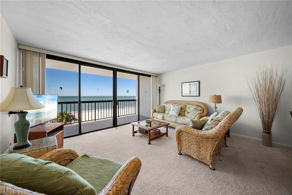 26300 Hickory Boulevard, Unit 503 Bonita Springs, FL 34134 - Photo 15 of 50 Living room featuring floor to ceiling windows, carpet floors, and a textured ceiling