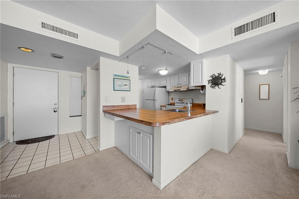 26300 Hickory Boulevard, Unit 503 Bonita Springs, FL 34134 - Photo 6 of 50 Kitchen with a peninsula, wood counters, light carpet, and white cabinetry