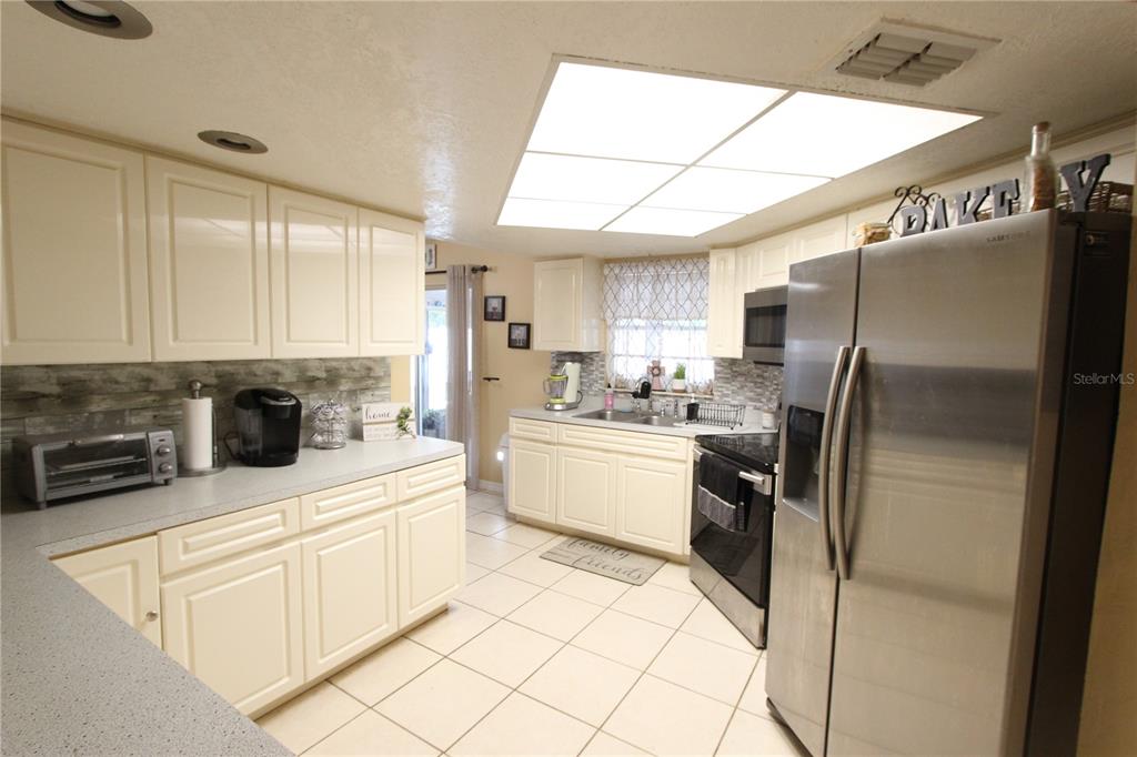 5046 Kenmore Street Spring Hill, FL 34608 - Photo 3 of 19 a kitchen with stainless steel appliances a refrigerator sink and cabinets