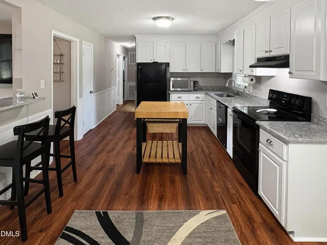 a kitchen with a wooden floor a sink a counter top space and stainless steel appliances