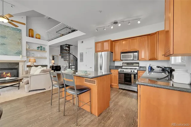 a kitchen with granite countertop a stove top oven a sink dishwasher a dining table and chairs with wooden floor