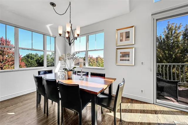 a dining room with wooden floor a chandelier a wooden table and chairs