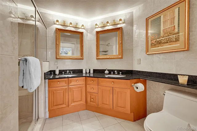 a bathroom with stainless steel appliances a sink a mirror and a refrigerator