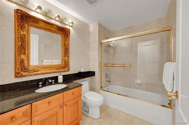 a bathroom with a granite countertop sink toilet a mirror and shower