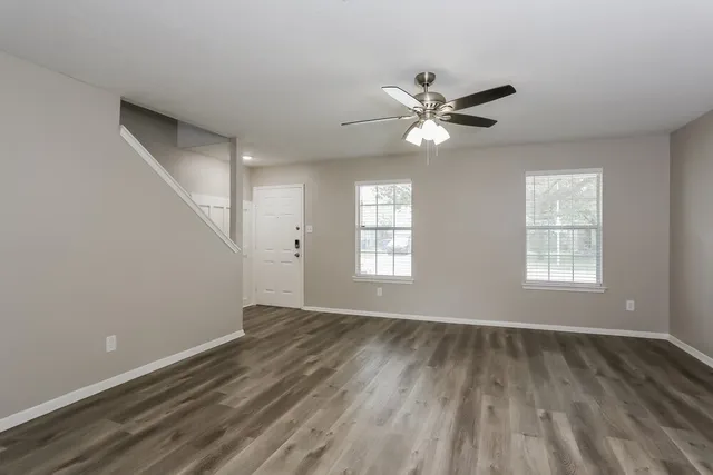 an empty room with wooden floor and windows