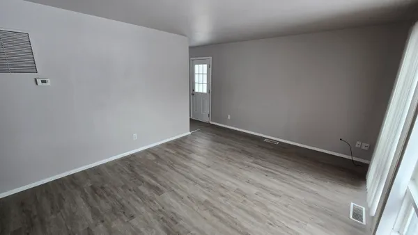 an empty room with wooden floor and windows