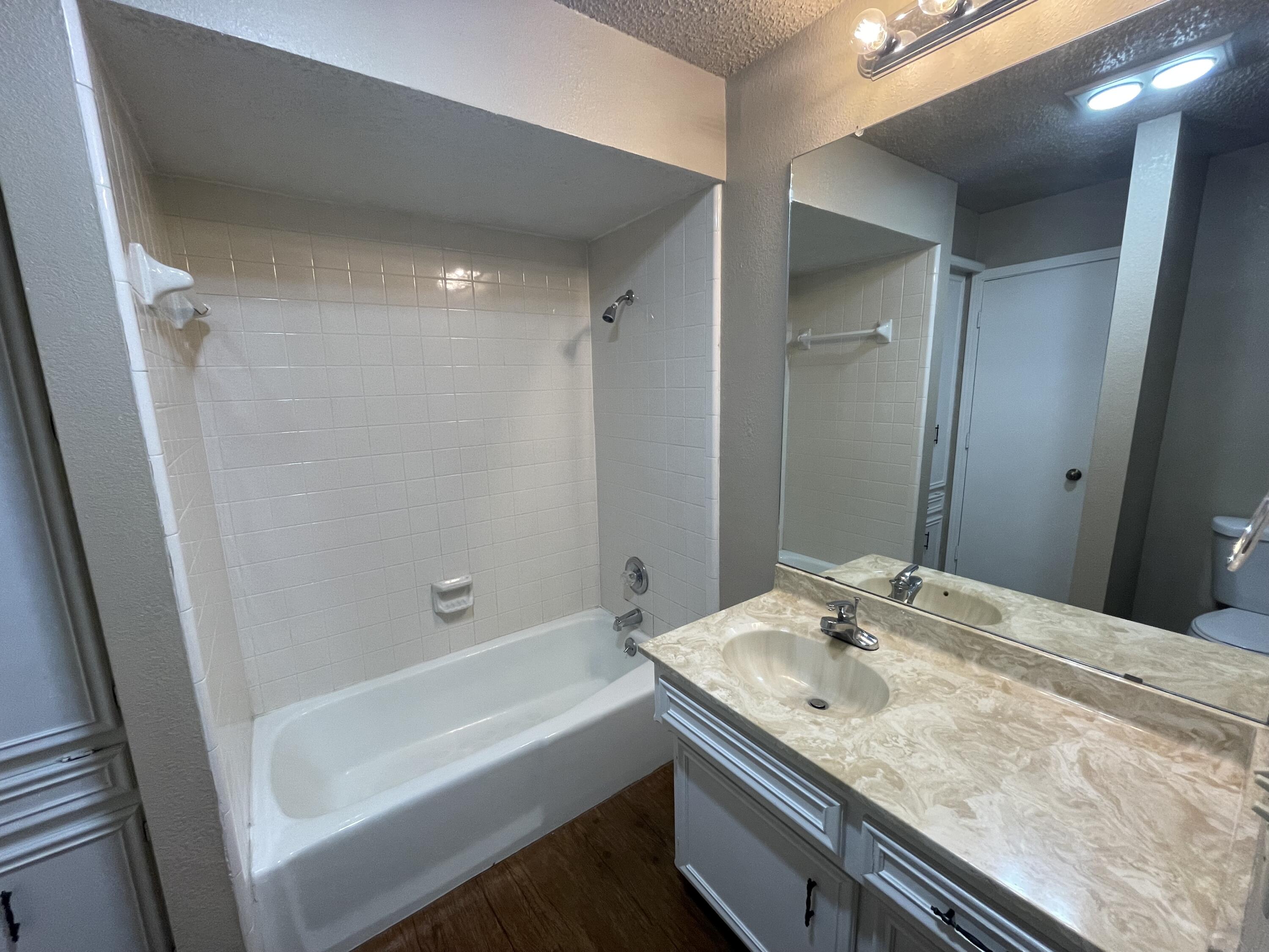 4413 75th Drive, Unit B Lubbock, TX 79424 - Photo 5 of 9 a bathroom with a granite countertop sink a mirror and a bathtub
