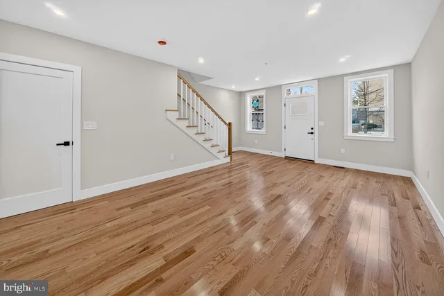 a view of an empty room with wooden floor and window