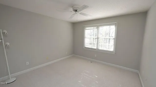 an empty room with a window and a ceiling fan