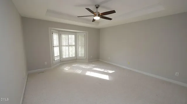 an empty room with windows and ceiling fan