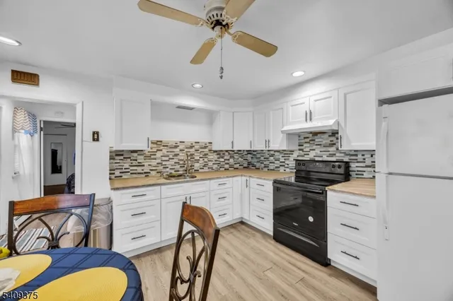 a kitchen with stainless steel appliances granite countertop a refrigerator a stove a sink dishwasher and white cabinets with wooden floor