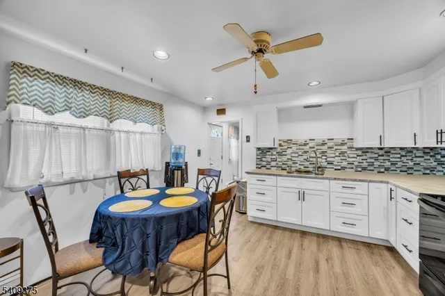 a kitchen with granite countertop a table chairs a sink dishwasher refrigerator and cabinets with wooden floor