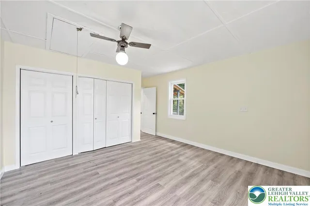 an empty room with wooden floor ceiling fan and windows