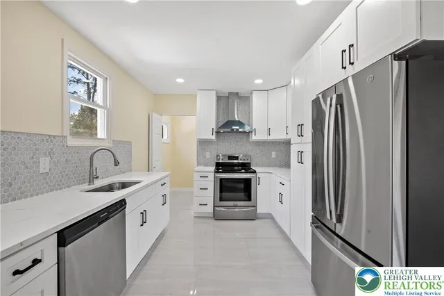 a kitchen with stainless steel appliances a refrigerator sink and white cabinets