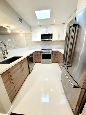 a kitchen with stainless steel appliances a refrigerator sink and microwave