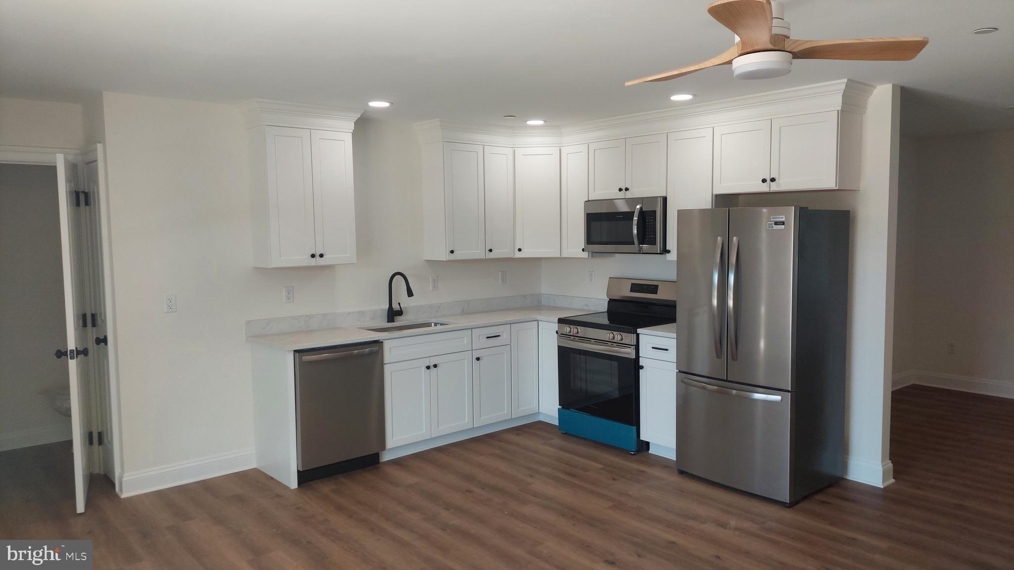 Michaels Way, Unit 1C East New Market, MD 21631 - Photo 2 of 12 a kitchen with stainless steel appliances granite countertop a refrigerator a stove top oven a sink and dishwasher with wooden floor