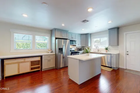 a kitchen with white cabinets and wooden floor