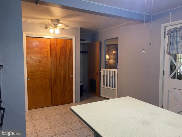 an empty room with chandelier fan and windows